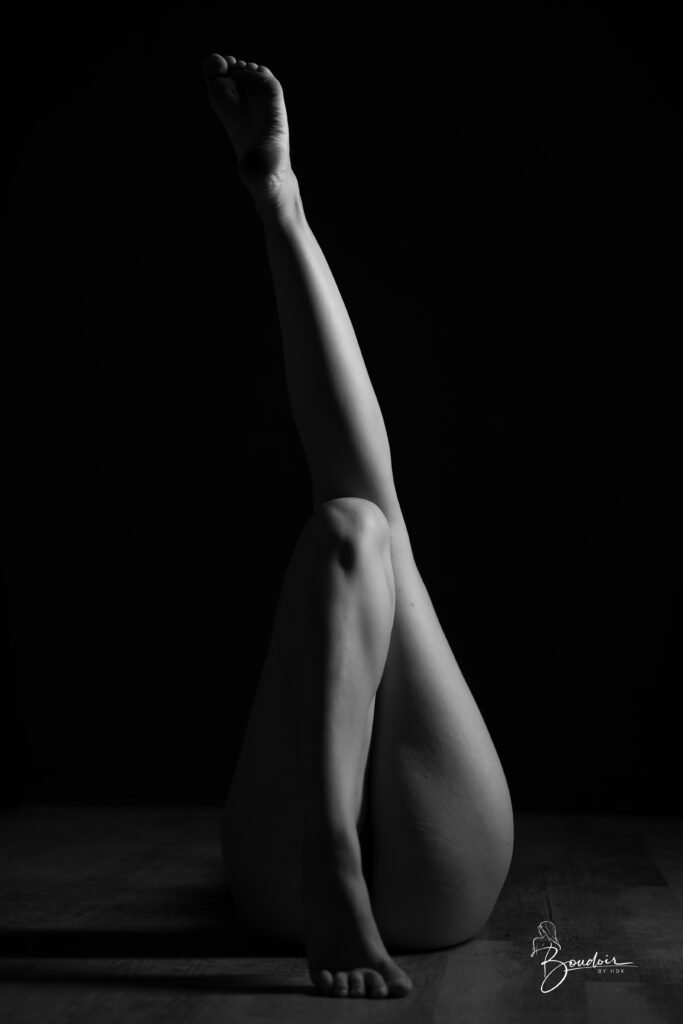 Venisis allongée au sol, les jambes tendues vers le haut et dessinées par une lumière latérale.