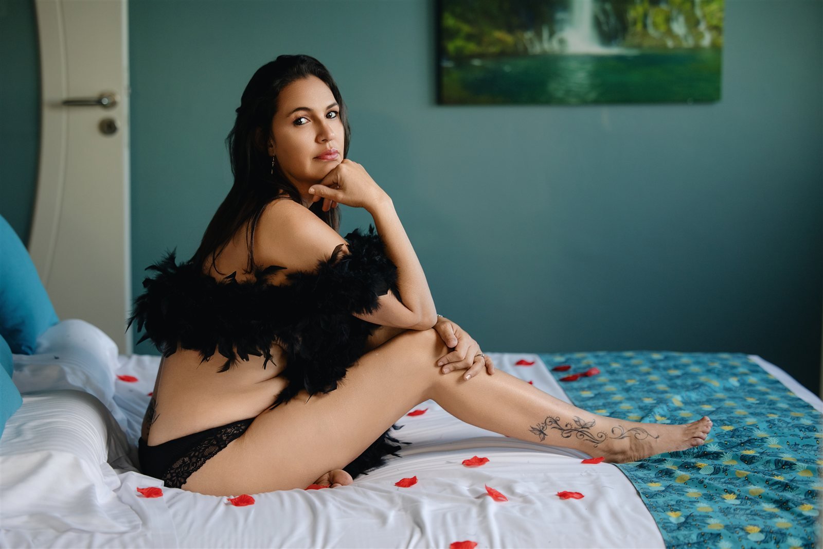 Sarah assise sur le lit d’une chambre d’hôtel, devant un mur bleu-vert.